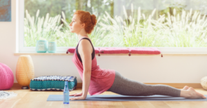 Moteris atlieka jogos pozą ant kilimėlio šviesioje patalpoje