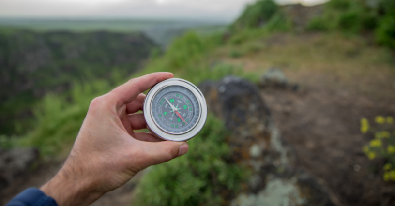 Asmuo laiko kompasą lauke žygiui