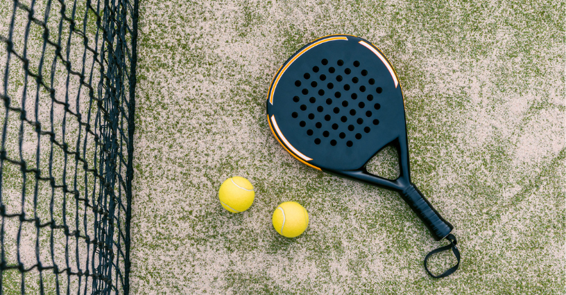 Padelio raketė ir kamuoliukai prie tinklo ant aikštelės